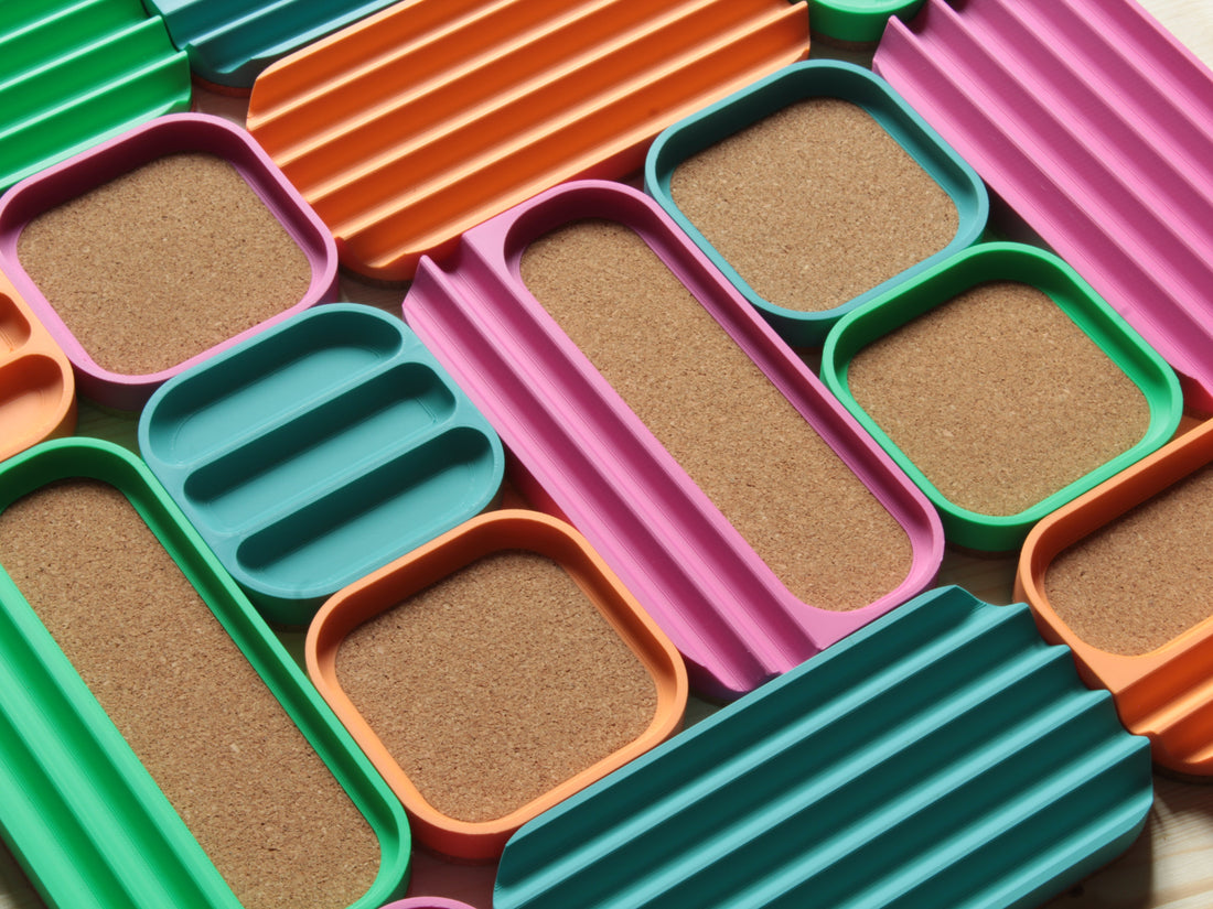 A colorful set of modern, bento-style desk organizers with different types of compartments, some of them with warm cork padding.