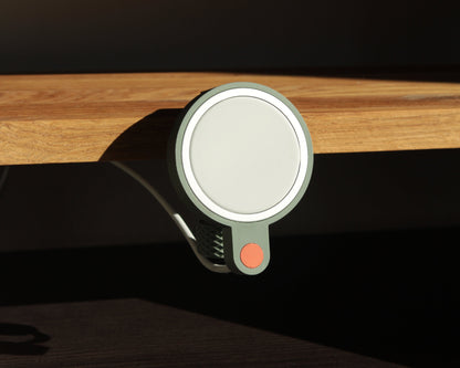 Close-up of a matte green magsafe holder clamp attached to a wooden surface with a dark background