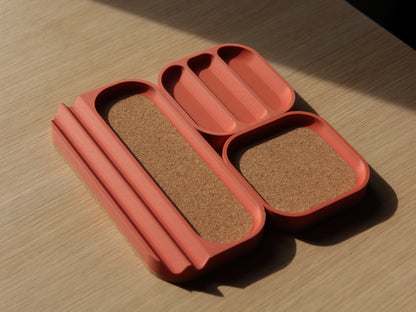 A set of brick orange modular trays with rounded corners and cork padding. There are 2 small square trays and a longer one with a cork-padded pocket