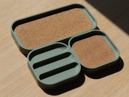 A set of sage green modular square trays with rounded corners and cork padding